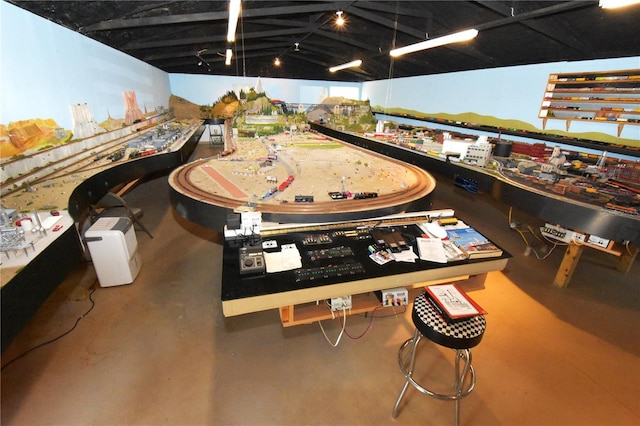 recreation room with lofted ceiling and concrete floors