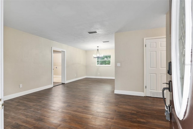 unfurnished room featuring an inviting chandelier and dark hardwood / wood-style floors