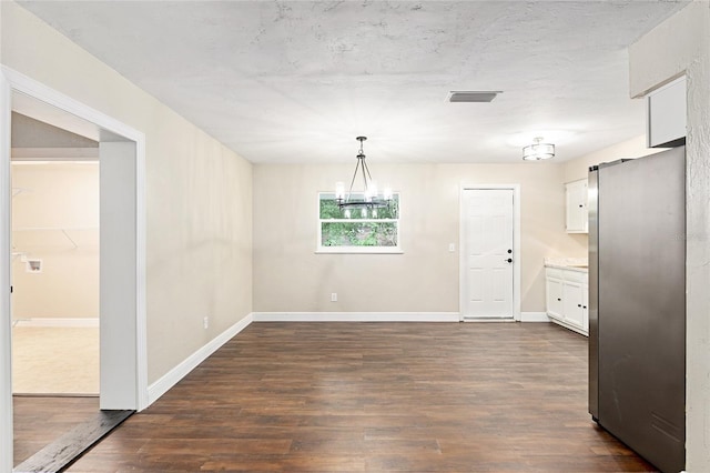 unfurnished dining area with dark wood-type flooring and an inviting chandelier