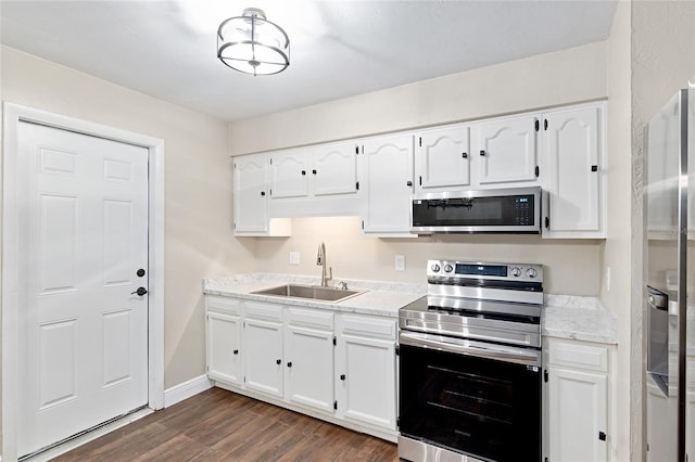 kitchen with sink, appliances with stainless steel finishes, white cabinetry, light stone countertops, and dark hardwood / wood-style flooring
