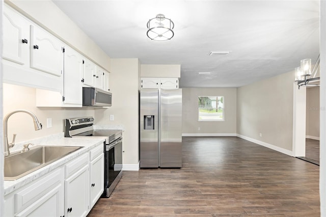 kitchen with stainless steel appliances, white cabinetry, sink, and dark wood-type flooring