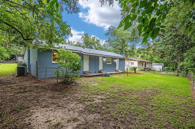 rear view of property featuring central AC unit, a lawn, and a porch