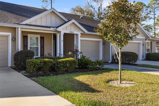 view of front facade with roof with shingles, concrete driveway, board and batten siding, a front yard, and a garage