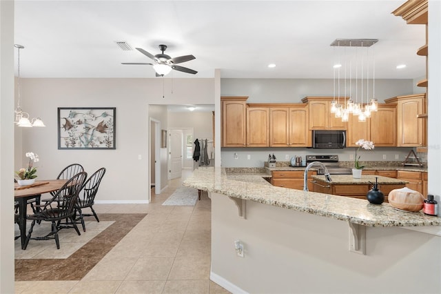 kitchen featuring hanging light fixtures, light stone counters, and a kitchen breakfast bar