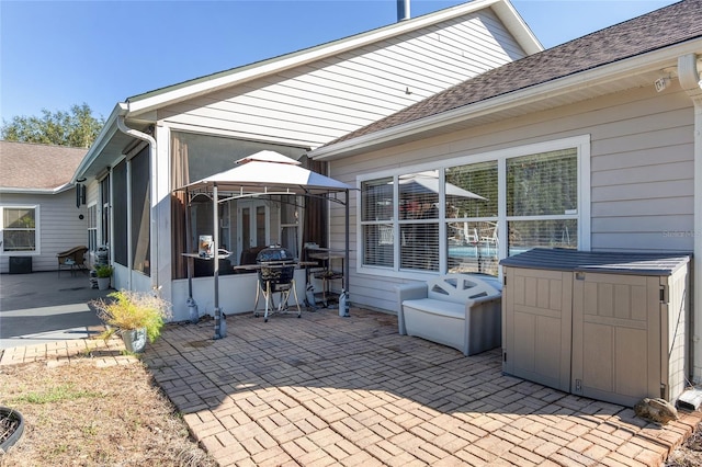 exterior space with a sunroom, a hot tub, grilling area, and a gazebo