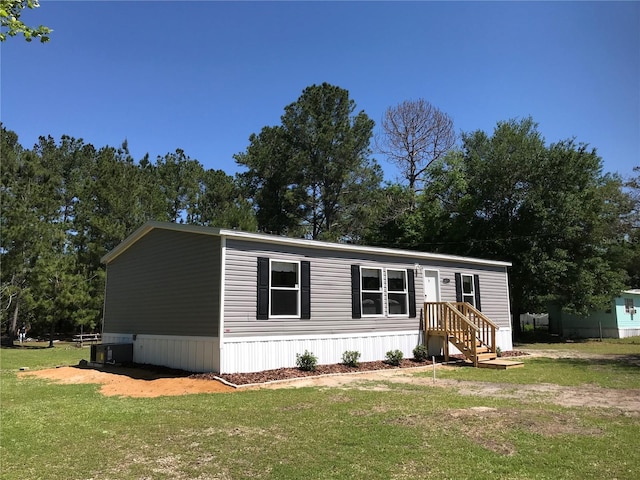 manufactured / mobile home featuring cooling unit and a front lawn