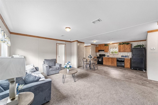 living area featuring carpet floors, visible vents, crown molding, and wood finished floors