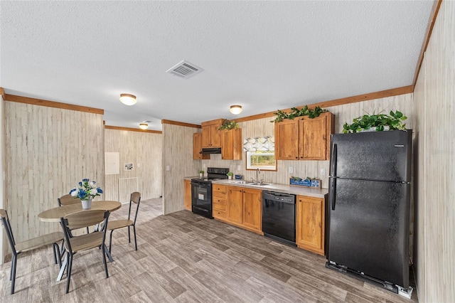 kitchen featuring light countertops, visible vents, a sink, under cabinet range hood, and black appliances