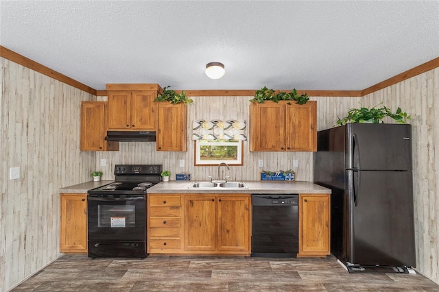 kitchen with light countertops, dark wood-type flooring, a sink, under cabinet range hood, and black appliances