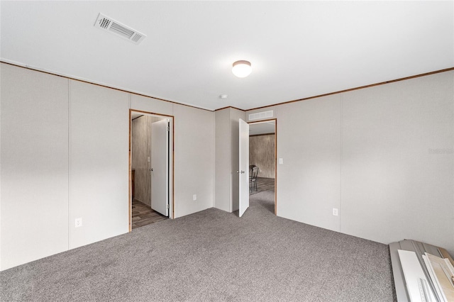 carpeted empty room with visible vents and crown molding