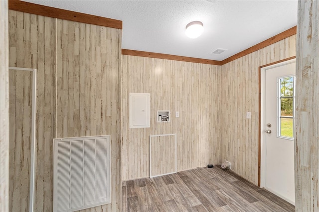 interior space with electric panel, visible vents, wooden walls, and wood finished floors