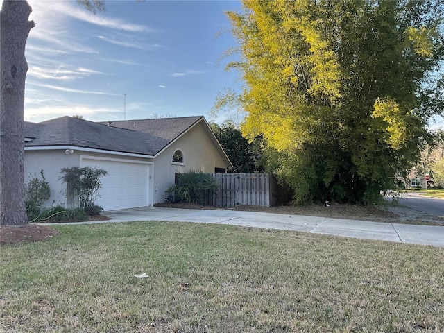 view of side of home with a garage, concrete driveway, fence, a yard, and stucco siding