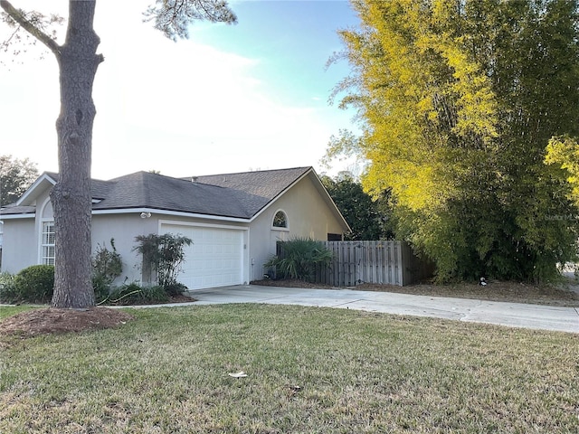 view of side of property with fence, driveway, an attached garage, and stucco siding