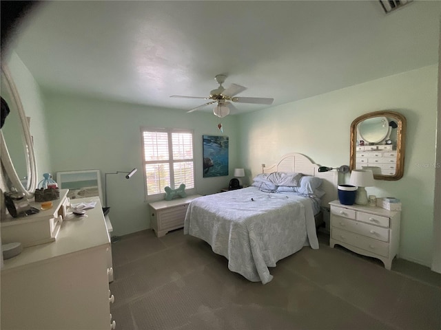 bedroom with visible vents, dark carpet, and a ceiling fan