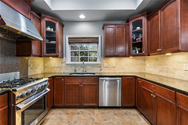 kitchen with dark stone counters, a sink, decorative backsplash, stainless steel appliances, and exhaust hood