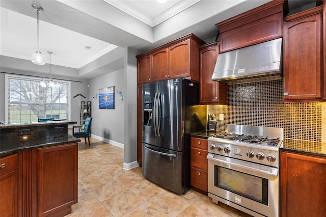 kitchen featuring ornamental molding, a tray ceiling, tasteful backsplash, appliances with stainless steel finishes, and wall chimney range hood