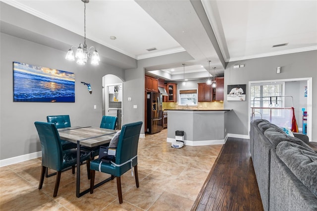 dining area featuring a tray ceiling, crown molding, arched walkways, and baseboards