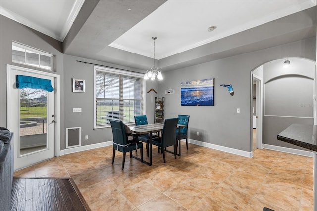 dining space with a tray ceiling, baseboards, a chandelier, and ornamental molding