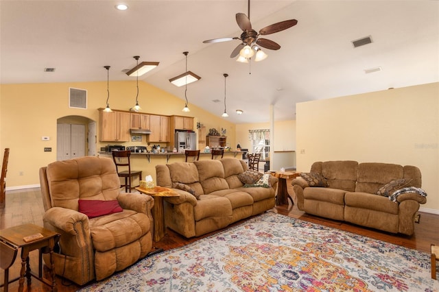 living area with wood finished floors, a ceiling fan, visible vents, and arched walkways