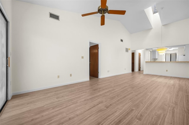 unfurnished living room with a skylight, high vaulted ceiling, ceiling fan, and light hardwood / wood-style flooring