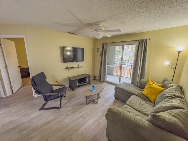 living area featuring a textured ceiling, ceiling fan, wood finished floors, and visible vents