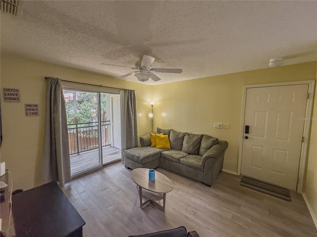 living room with a ceiling fan, a textured ceiling, visible vents, and wood finished floors