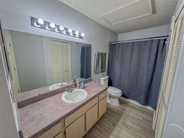 bathroom featuring a textured wall, toilet, a textured ceiling, vanity, and wood finished floors