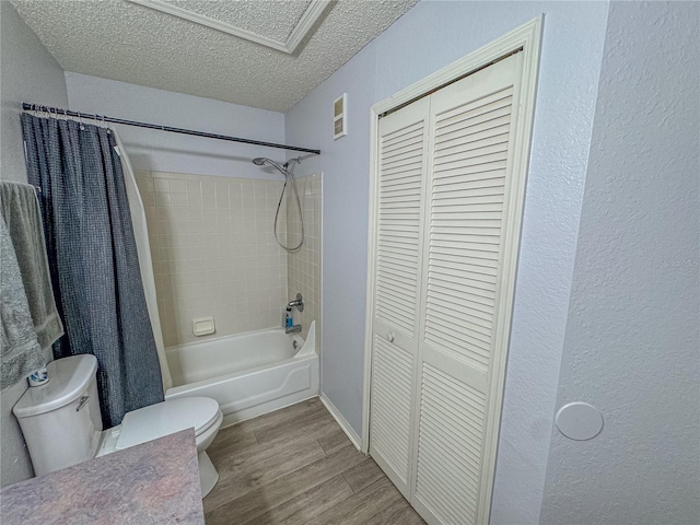 bathroom with a textured ceiling, toilet, wood finished floors, a closet, and shower / bath combo