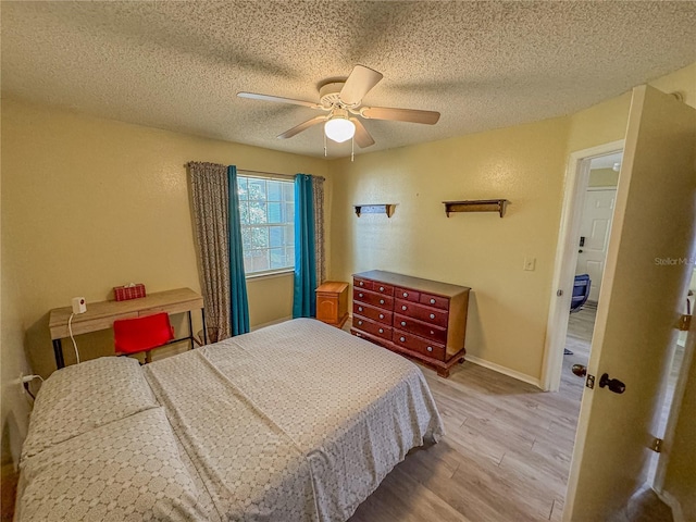 bedroom with a textured ceiling, a textured wall, a ceiling fan, baseboards, and light wood finished floors