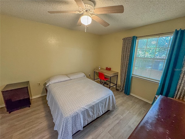 bedroom featuring ceiling fan, a textured ceiling, baseboards, and wood finished floors