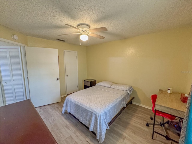 bedroom with visible vents, light wood-style floors, ceiling fan, a textured ceiling, and baseboards