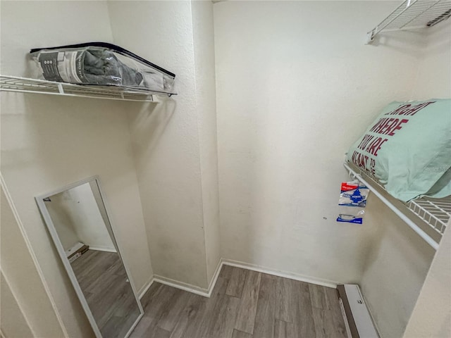 laundry area with baseboard heating, wood finished floors, and baseboards