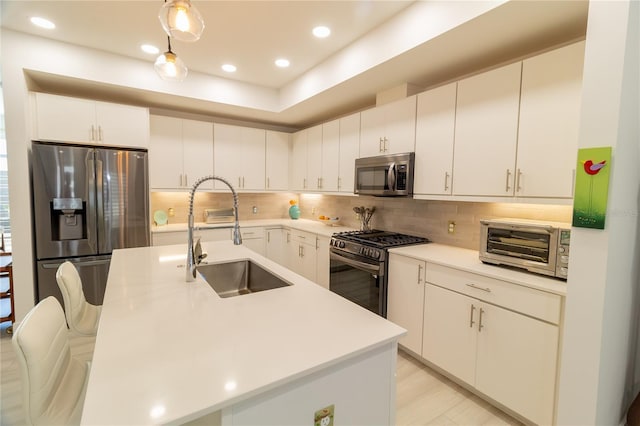 kitchen featuring a toaster, a sink, decorative backsplash, light countertops, and stainless steel appliances