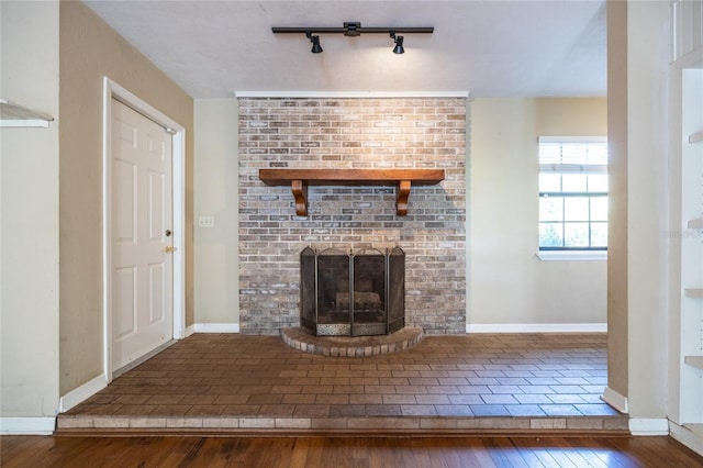 unfurnished living room with a brick fireplace, baseboards, and hardwood / wood-style flooring