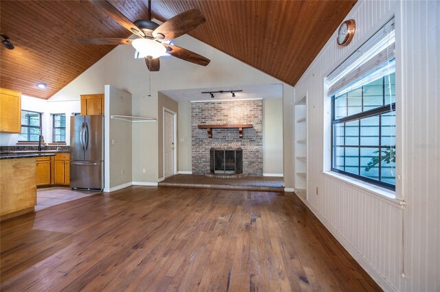 unfurnished living room featuring built in shelves, a fireplace, rail lighting, wooden ceiling, and hardwood / wood-style flooring