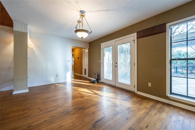 empty room featuring french doors, hardwood / wood-style floors, and baseboards