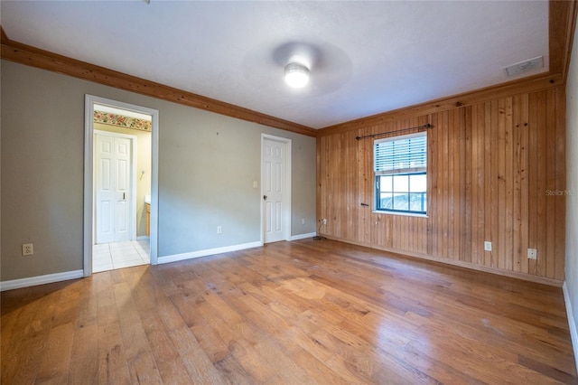 spare room with baseboards, wooden walls, visible vents, and hardwood / wood-style floors