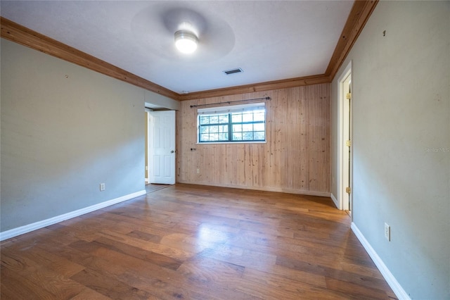 spare room featuring visible vents, baseboards, wood finished floors, and ornamental molding