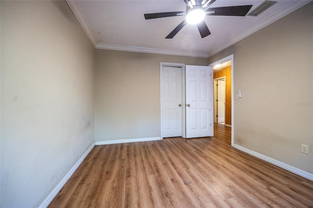 unfurnished bedroom with baseboards, visible vents, ornamental molding, light wood-type flooring, and a closet