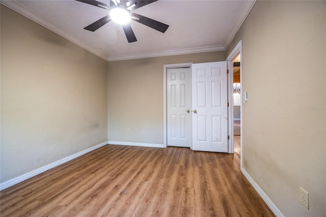 unfurnished bedroom with baseboards, ceiling fan, ornamental molding, wood finished floors, and a closet