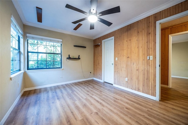 empty room with ceiling fan, ornamental molding, wood finished floors, and baseboards