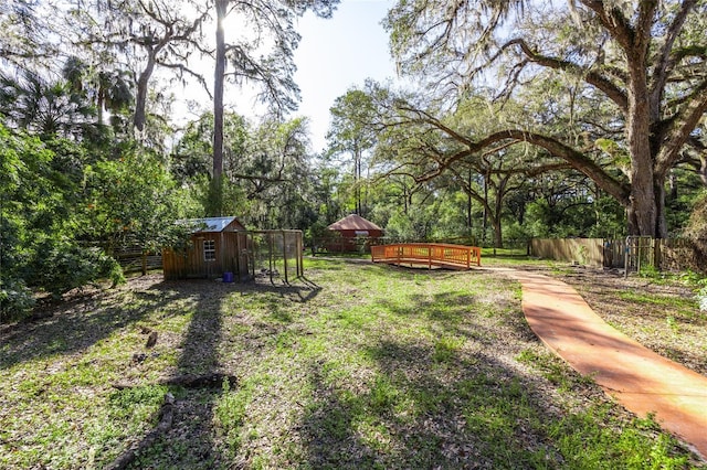 view of yard featuring fence private yard, a wooden deck, a storage unit, and an outbuilding