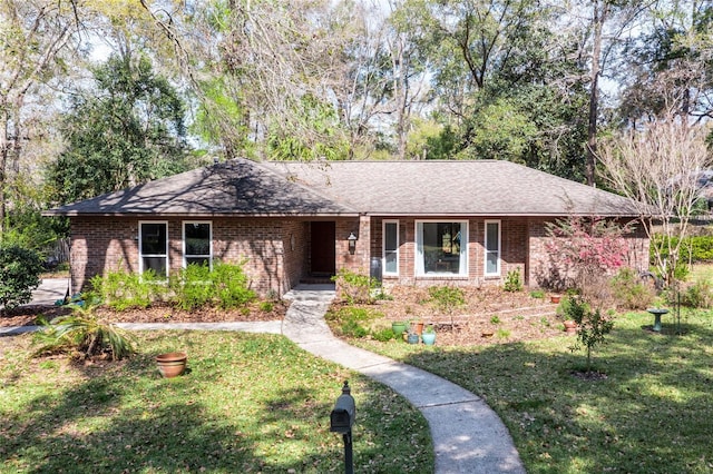 ranch-style home with brick siding, a front yard, and a shingled roof