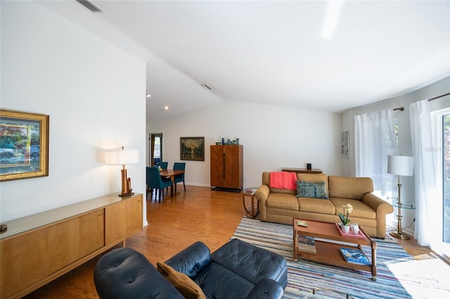 living room with vaulted ceiling, light wood-style flooring, and visible vents