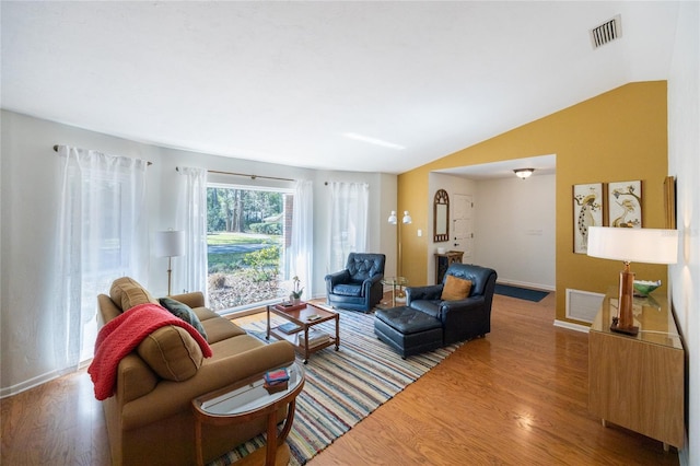 living room with vaulted ceiling, wood finished floors, and visible vents