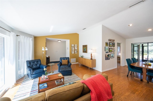 living area with vaulted ceiling, wood finished floors, and visible vents