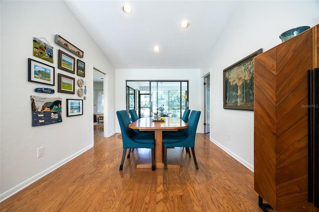 dining space featuring recessed lighting, baseboards, wood finished floors, and vaulted ceiling