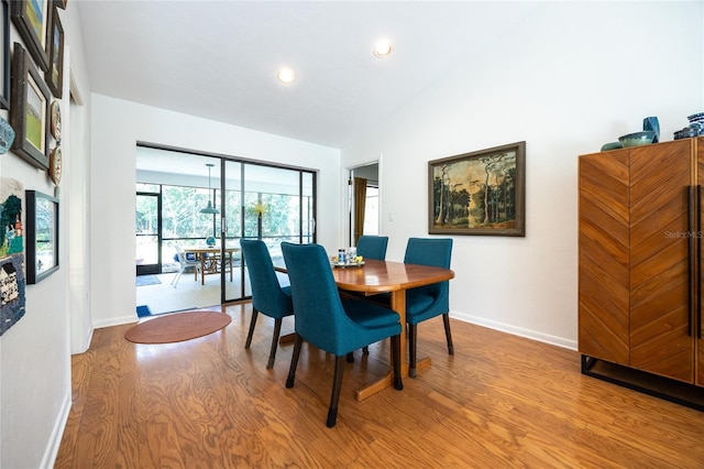 dining area with recessed lighting, baseboards, wood finished floors, and vaulted ceiling