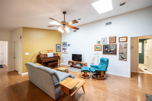 living area with a skylight, wood finished floors, visible vents, and baseboards