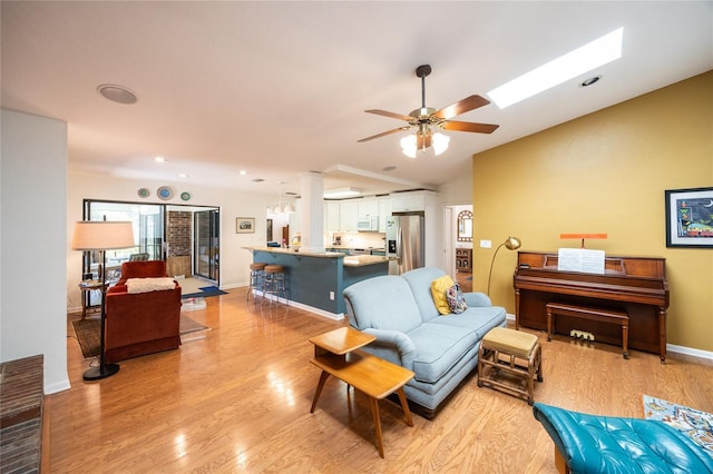 living room with baseboards, lofted ceiling, light wood-style floors, and a ceiling fan